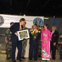 Presentation of Plaque & Roses to Hmong Community TJ is presenting a plaque to men and women in Chinese national costumes