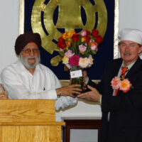 Presentation of Vase of Roses to Sikh Community two men in head pieces are holding a vase with roses